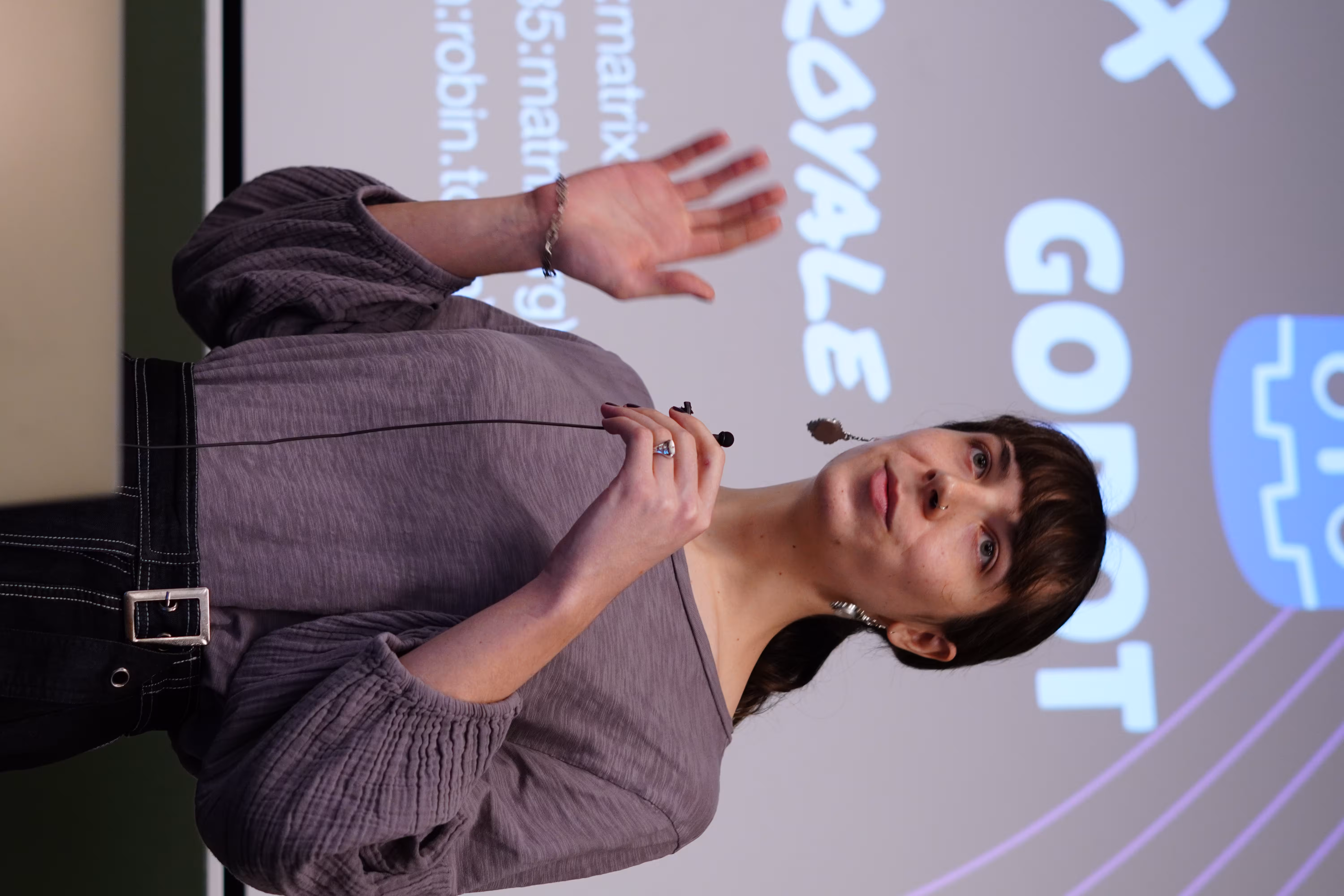 A portrait of Robin, a woman giving a talk in front of their slides. In the background we can read the word "Godot" on her slides.